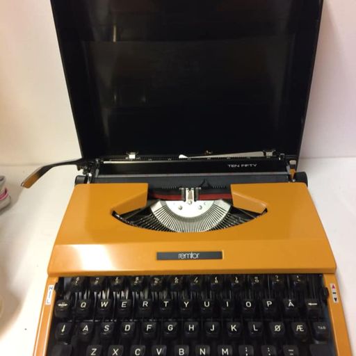 En oransje retro skrivemaskin på salg i en gjenbruksbutikk