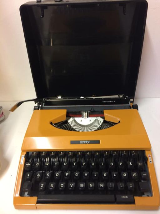 En oransje retro skrivemaskin på salg i en gjenbruksbutikk