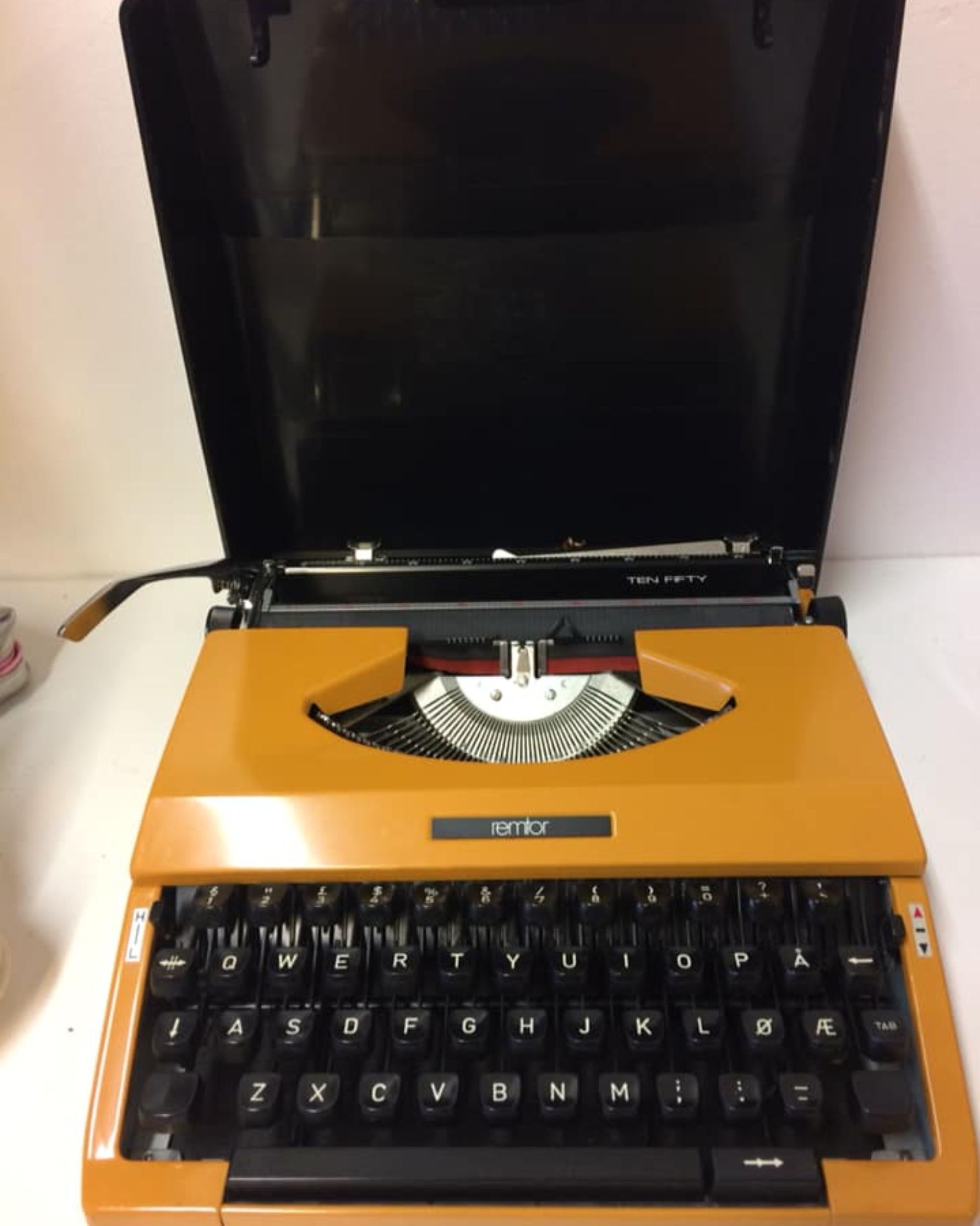 En oransje retro skrivemaskin på salg i en gjenbruksbutikk